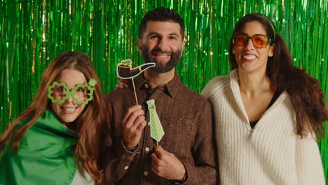 Studio-Portrait-Shot-Of-Friends-Dressing-Up-With-Irish-Novelties-And-Props-Celebrating-St-Patrick's-Day-Against-Green-Tinsel-Background-1